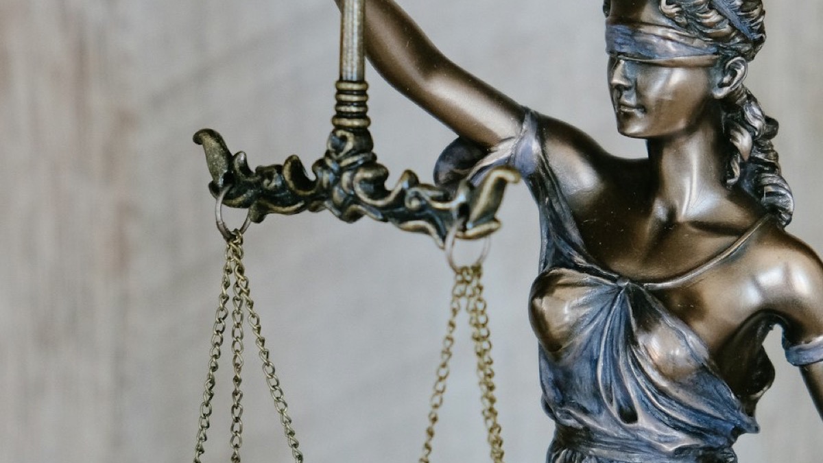 A bronze statue of Lady Justice holding balanced scales